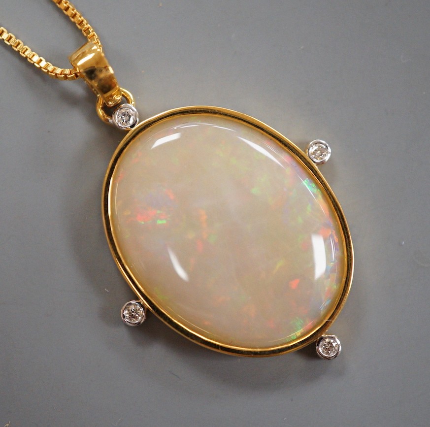 A modern 9k single stone white opal and four stone diamond set oval pendant, overall 42mm, on a gilt metal chain, the opal weighing approx. 10.00ct.